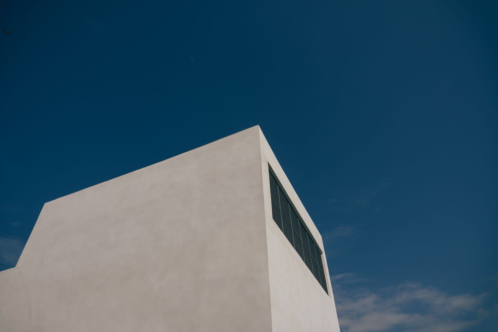 Sharp angles of a minimalist building against a clear blue sky, showcasing modern design.